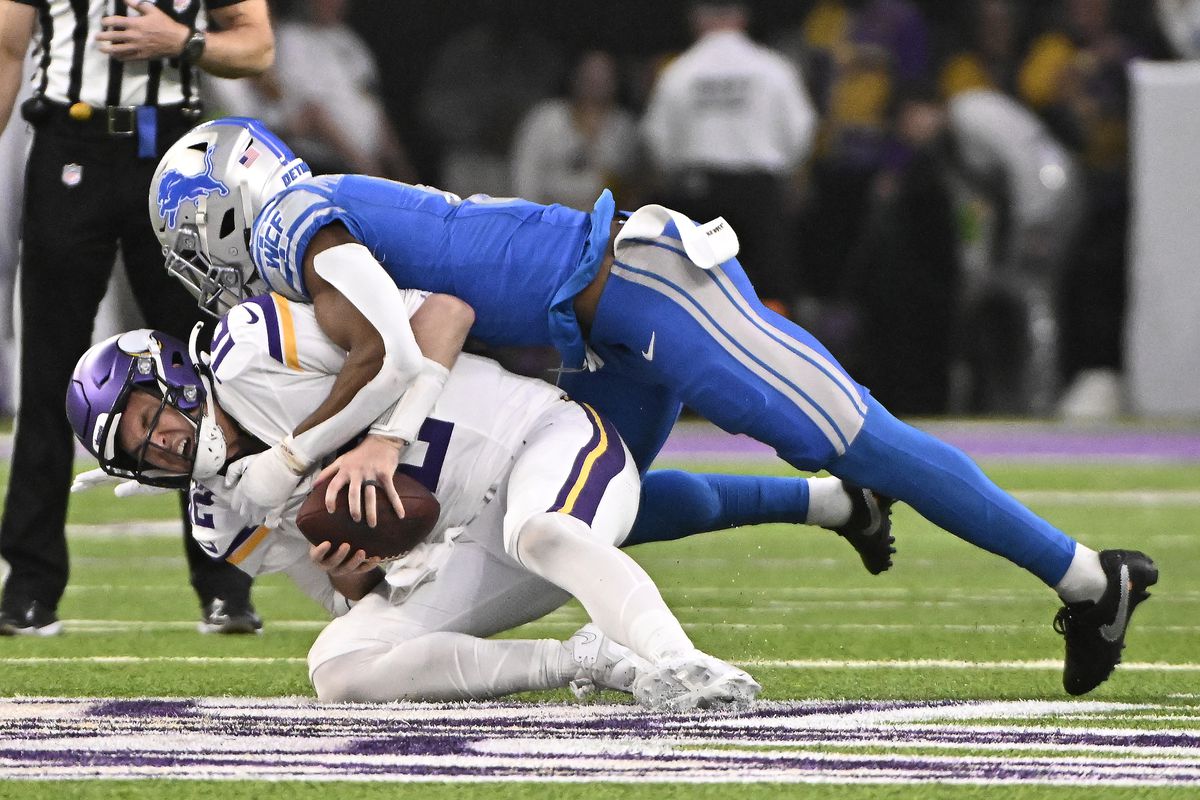 Nick Mullens #12 of the Minnesota Vikings is sacked by Ifeatu Melifonwu #6 of the Detroit Lions during the second quarter at U.S. Bank Stadium on December 24, 2023 in Minneapolis, Minnesota.