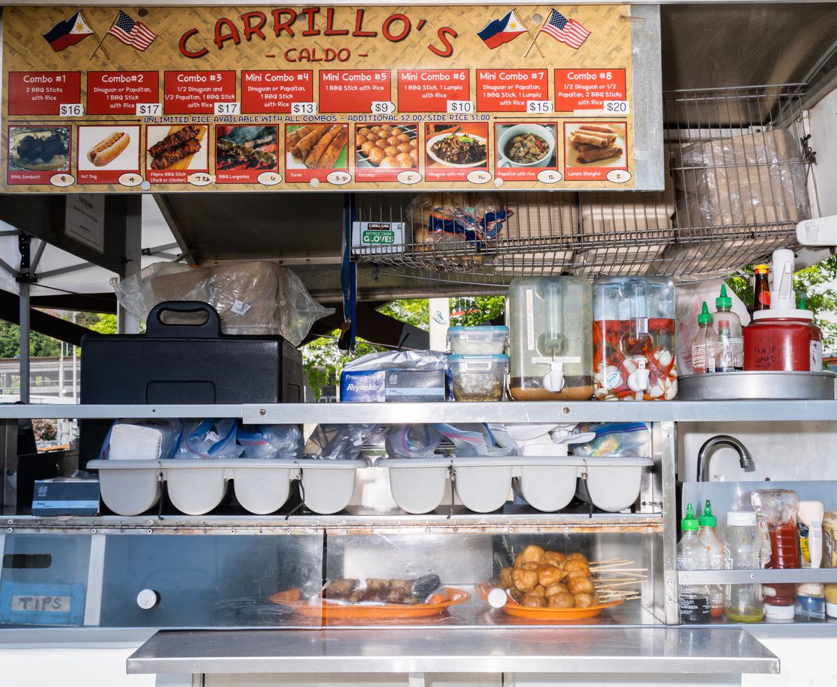 The inside of a food cart, with a sign that says “Carillo’s” listing off many Filipino delicacies. 