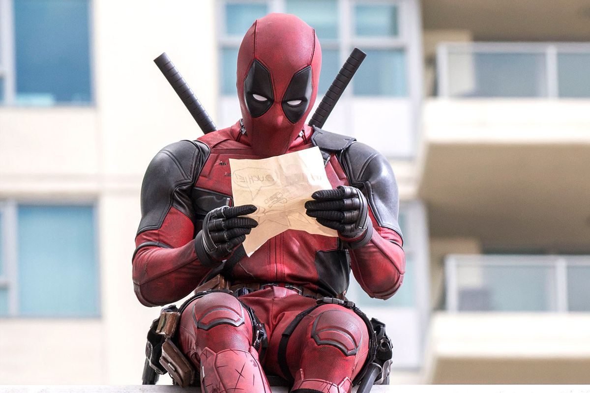 Deadpool reading a note while sitting on a highway.