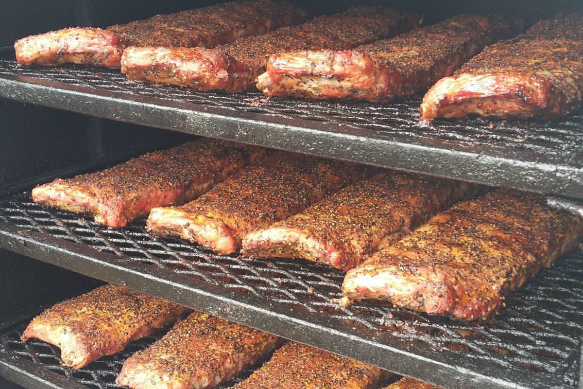 Smoked briskets on iron grate shelves inside a barbecue smoker 