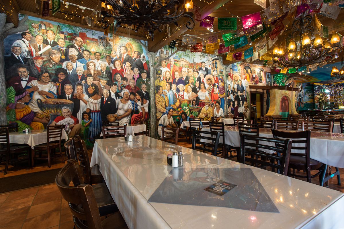 A dining room with tables and chairs and a giant painted mural on the back wall. 