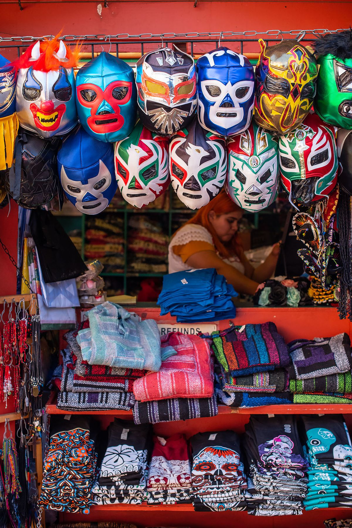 Vendor at Olvera Street selling luchador masks, T-shirts, and more