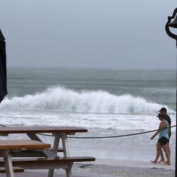 Waves kick up as people walk on Pass-a Grille Beach, St. Pete Beach, Fla., Monday, July 31, 2017. Tropical Storm Emily began trekking east across the Florida peninsula on Monday, scattering drenching rains amid expectations it would begin weakening in the coming hours on its approach to the Atlantic coast. (Scott Keeler/Tampa Bay Times via AP)