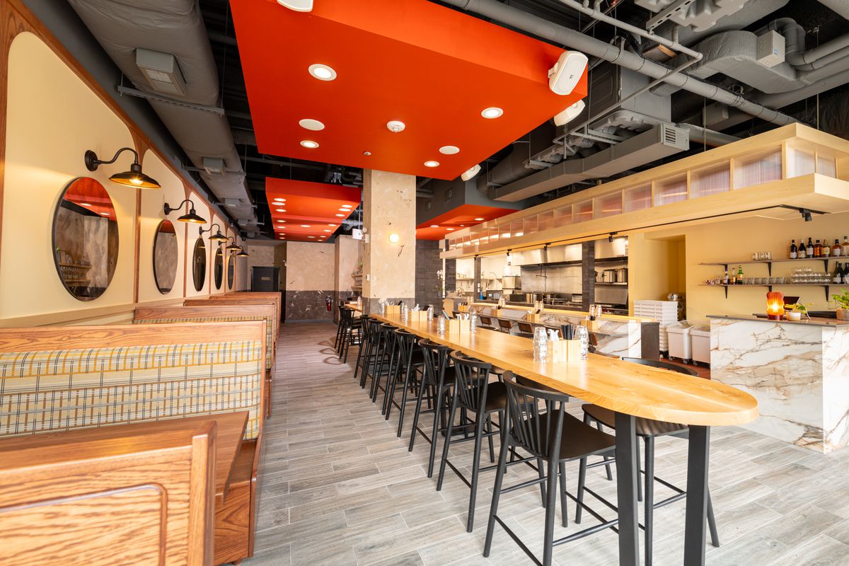 A large ramen restaurant with booths along one wall and a long communal table in the center.