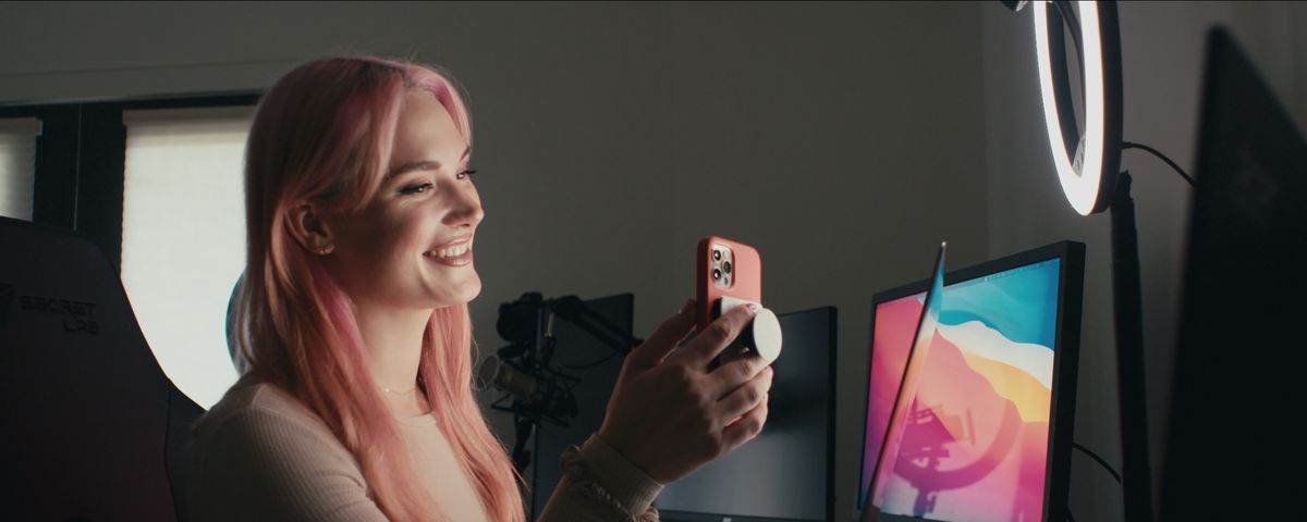 X-rated movie star Siri Dahl sits in front of a bank of monitors and smiles as she looks at a pink cellphone in a shot from the Netflix documentary Money Shot: The Pornhub Story