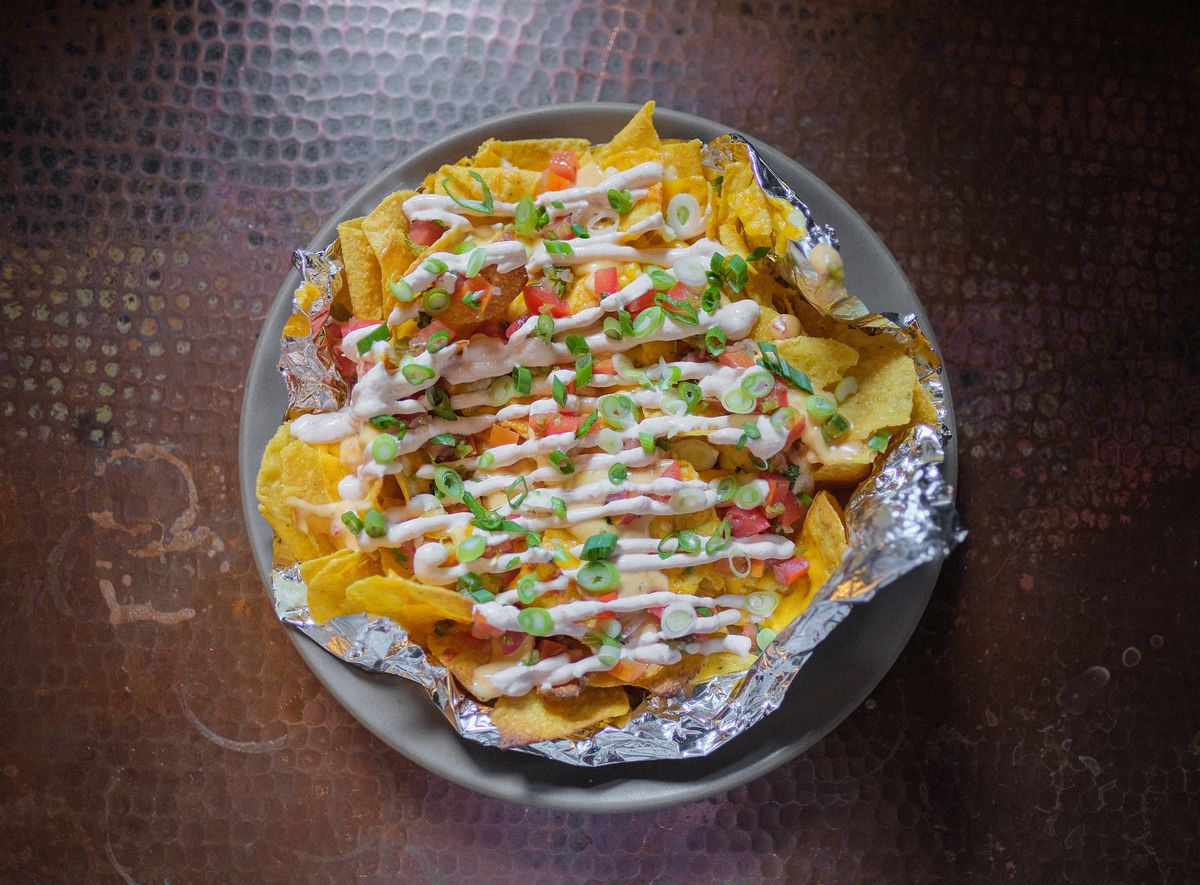 A plate of sour-cream-streaked nachos topped with green onion.