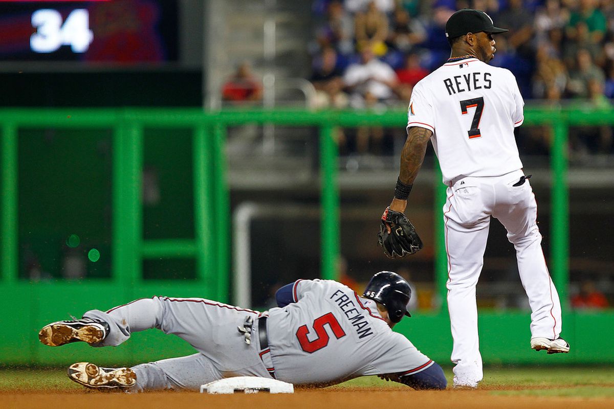 MIAMI, FL - JUNE 06: Jose Reyes #7 of the Miami Marlins turns a double play as Freddie Freeman #5 of the Atlanta Braves slides into second during a game  at Marlins Park on June 6, 2012 in Miami, Florida.  (Photo by Mike Ehrmann/Getty Images)