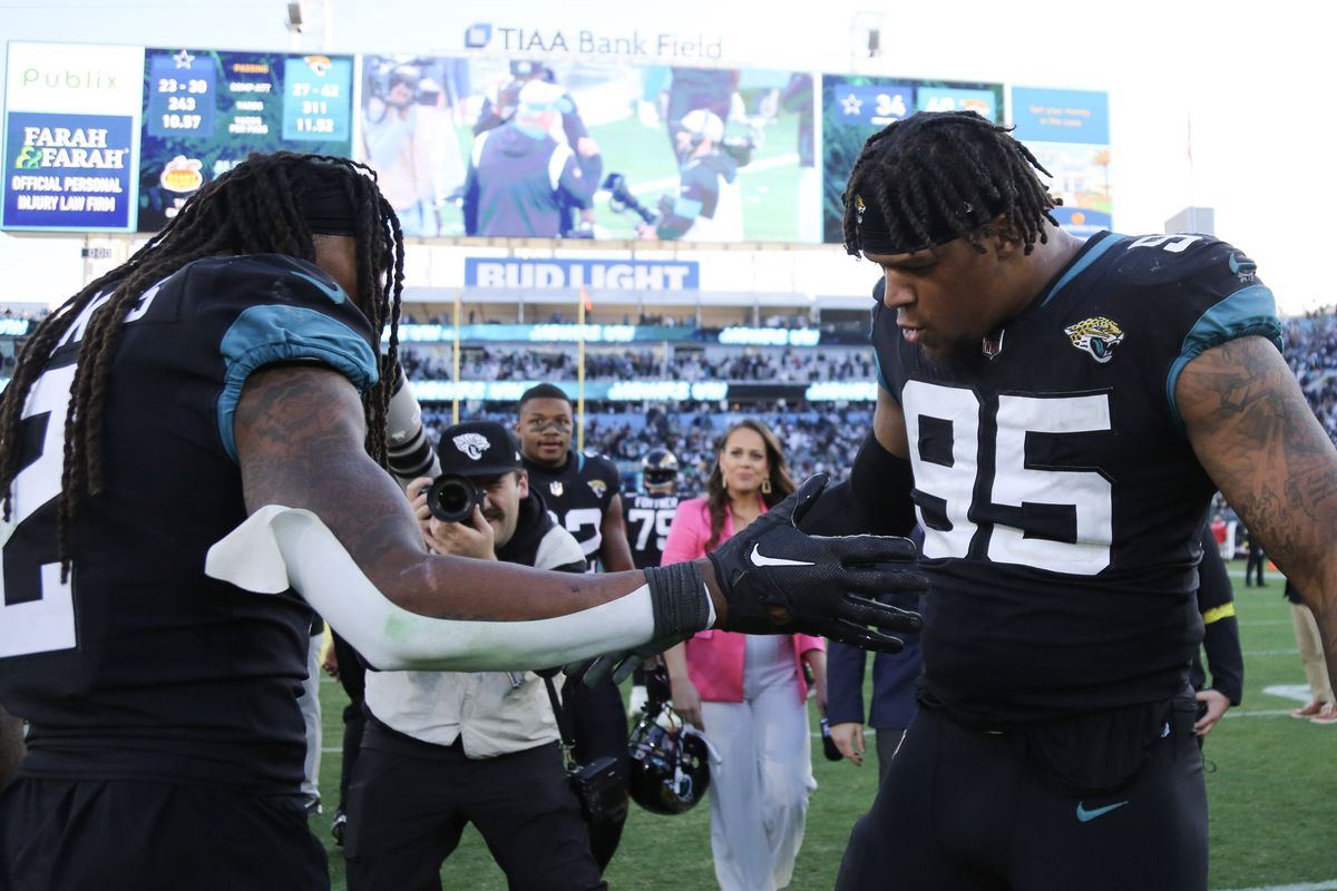 Roy Robertson-Harris #95 of the Jacksonville Jaguars celebrates with Rayshawn Jenkins #2 after defeating the Dallas Cowboys in overtime at TIAA Bank Field on December 18, 2022 in Jacksonville, Florida.