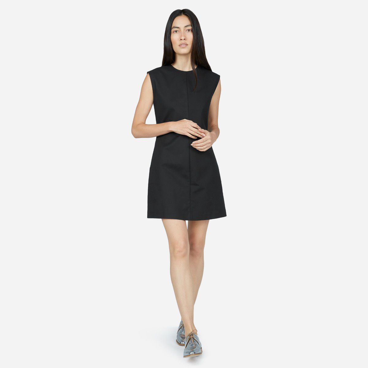 A model wearing an Everlane black flare dress with pockets