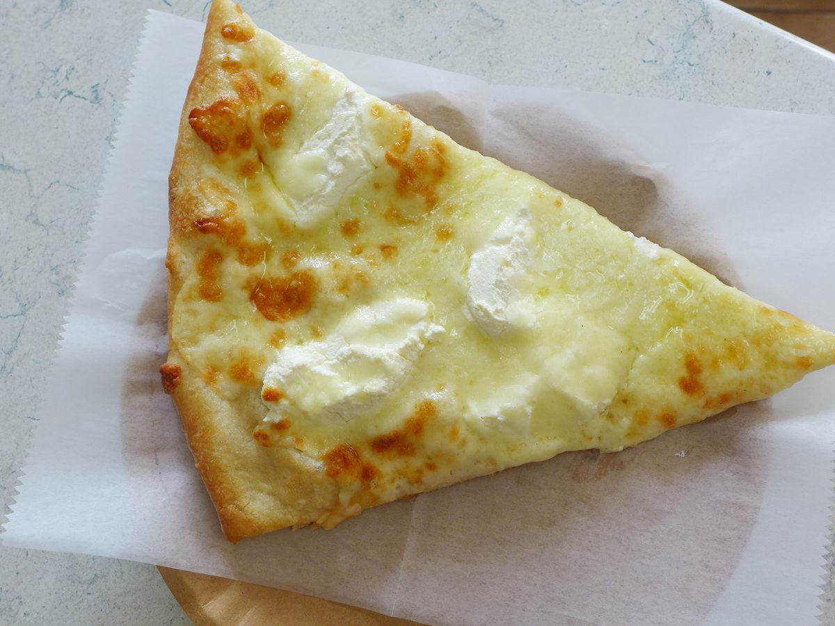 A white wedge with yellowish cheese and dabs of whitish ricotta on top.