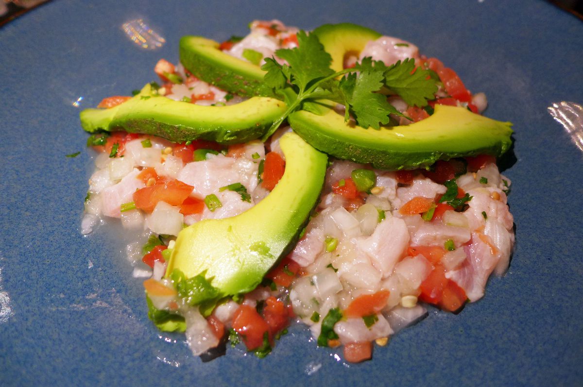 A compact mass of minced fish and tomatoes with avocado slices on top.