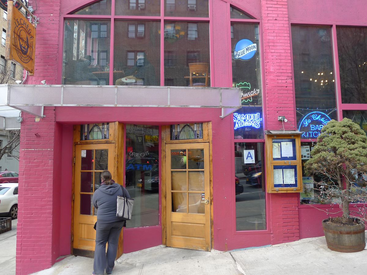 A two-story pink structure with a figure going in through a door.