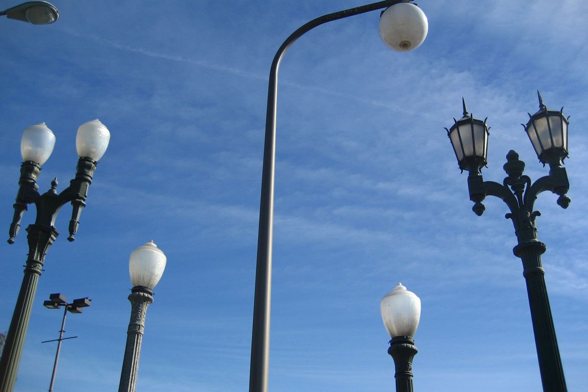 A photo of the tops of streetlights against a background of blue sky.
