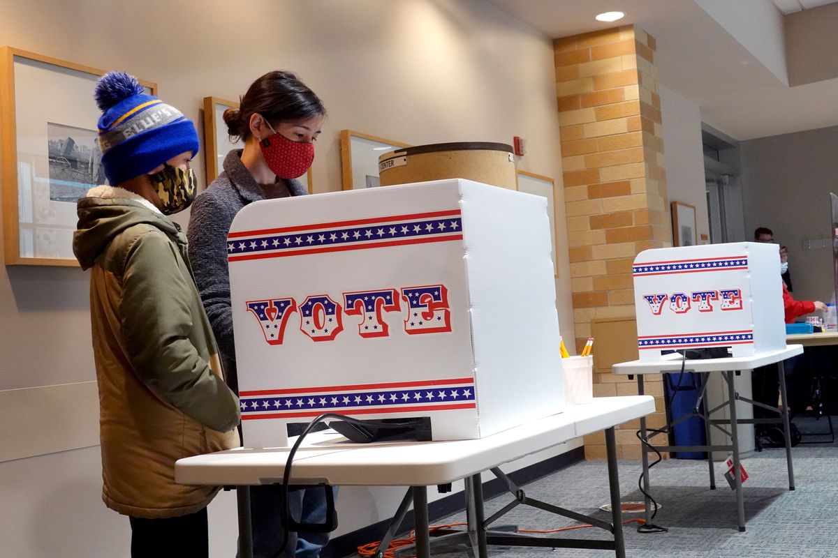 A voter in Milwaukee, Wisconsin casts an early ballot in October 2020 with her son.