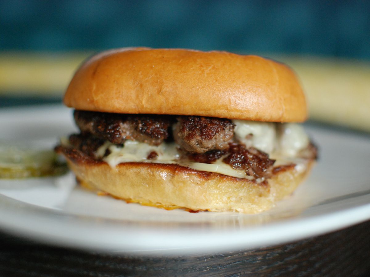 A skinny burger on a buttery bun with white cheese
