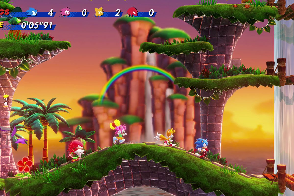 Knuckles, Amy, Tails, and Sonic the Hedgehog run through a level of Sonic Superstars with a waterfall, rainbow, and sunset in the background