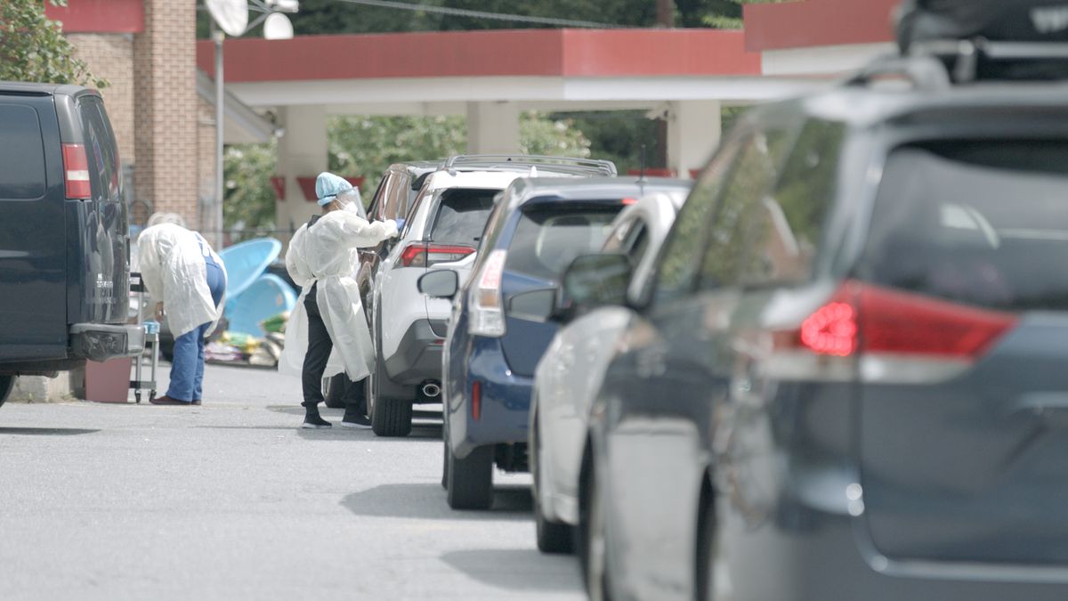 Cars line up for drive-through coronavirus tests in the documentary Totally Under Control