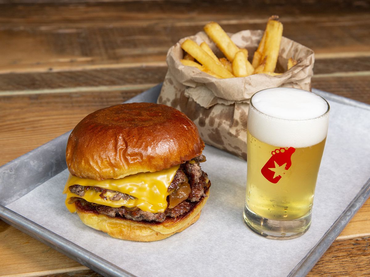 A cheeseburger, basket of fries, and a small pint of beer.