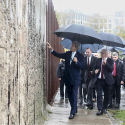 United States Secretary of State John Kerry, left, touches the remains of the  Berlin Wall during a visits at the Wall memorial site prior to a news conference with German Foreign Minister Frank-Walter Steinmeier , third left, in Berlin, Wednesday, Oct. 22, 2014.