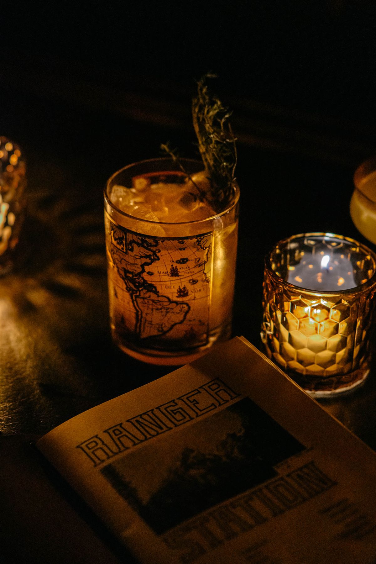 A cocktail beside a votive candle at the dark and cozy bar Ranger Station in Atlanta.