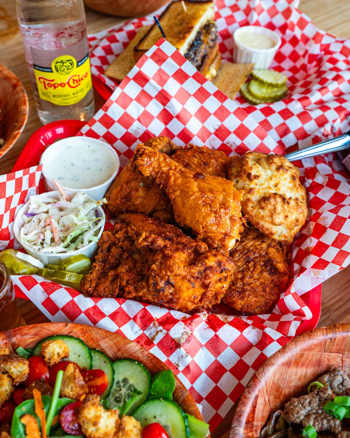 Fried chicken and sides in trays lined with red-and-white-squared wax paper.