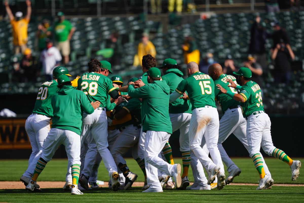 Ramon Laureano #22 of the Oakland Athletics celebrates with his teammates after reaching first on an error to walk off in the tenth inning against the Minnesota Twins at RingCentral Coliseum on April 21, 2021 in Oakland, California.