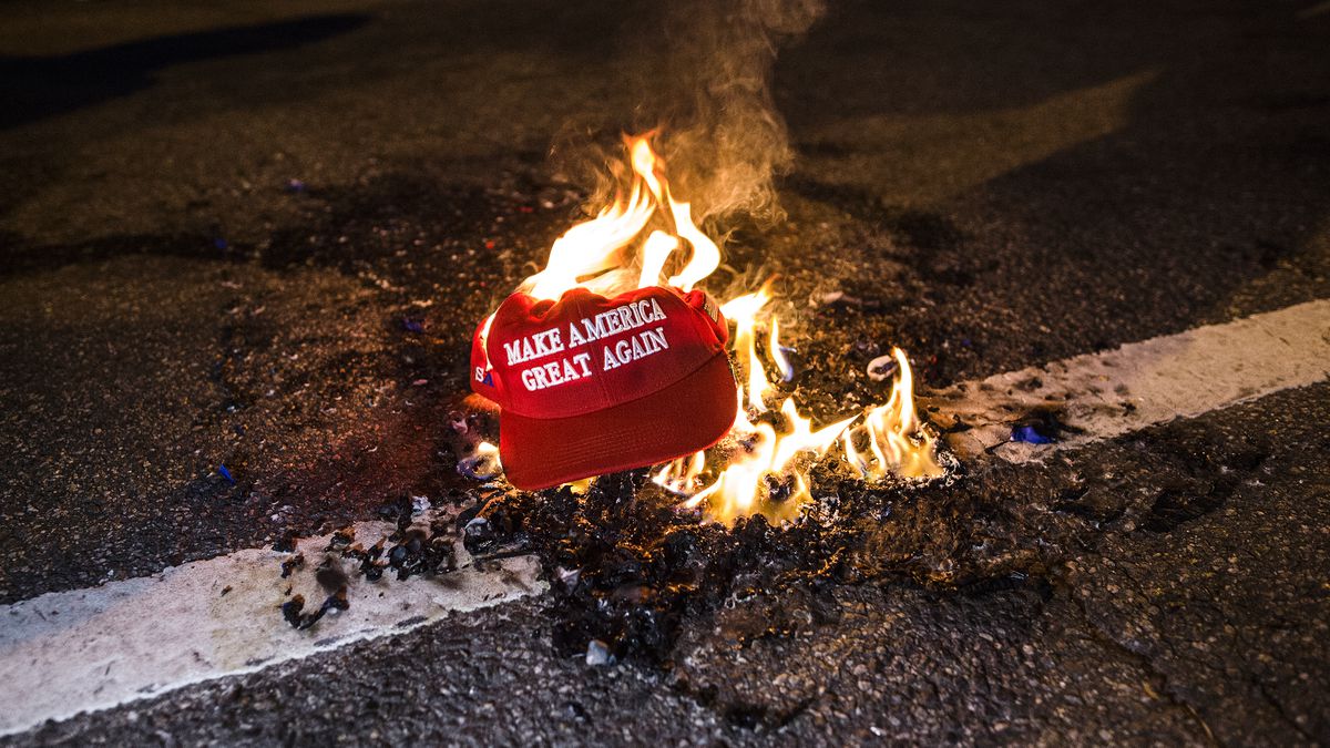 A red MAGA hat on fire in the road.