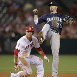 Seattle Mariners shortstop Brendan Ryan, right, watches his throw go to first base after forcing out Los Angeles Angels' Mike Trout, left, during the fifth inning of a baseball game in Anaheim, Calif., Tuesday, June 18, 2013. Los Angeles Angels' Josh Hamilton was out at first. 