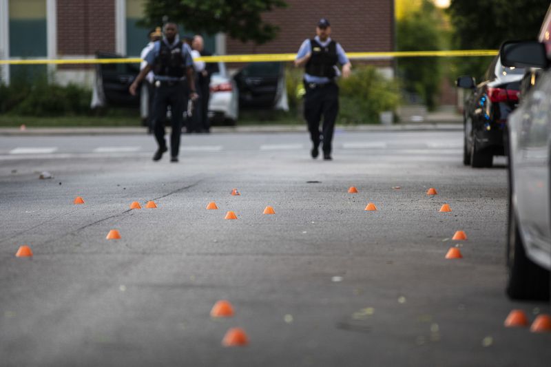 Dozens of evidence markers sit in the roadway in the 700 block of North Spaulding Avenue, where a 40-year-old man was shot multiple times while he was riding in a car on the West Side on Memorial Day.