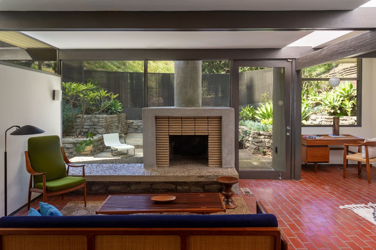 A room with brick floors, glass walls, and a fireplace