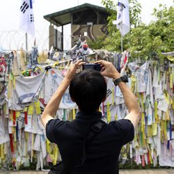 A visitors takes pictures in front of  wire fences decorated with ribbons written with messages wishing for the reunification of the two Koreas at the Imjingak Pavilion near the border village of the Panmunjom in Paju, South Korea, Friday, June 7, 2013.  North Korea on Friday proposed working-level talks with South Korea to be held in a border city on Sunday as the rivals look to mend ties that have plunged during recent years amid hardline stances by both countries.