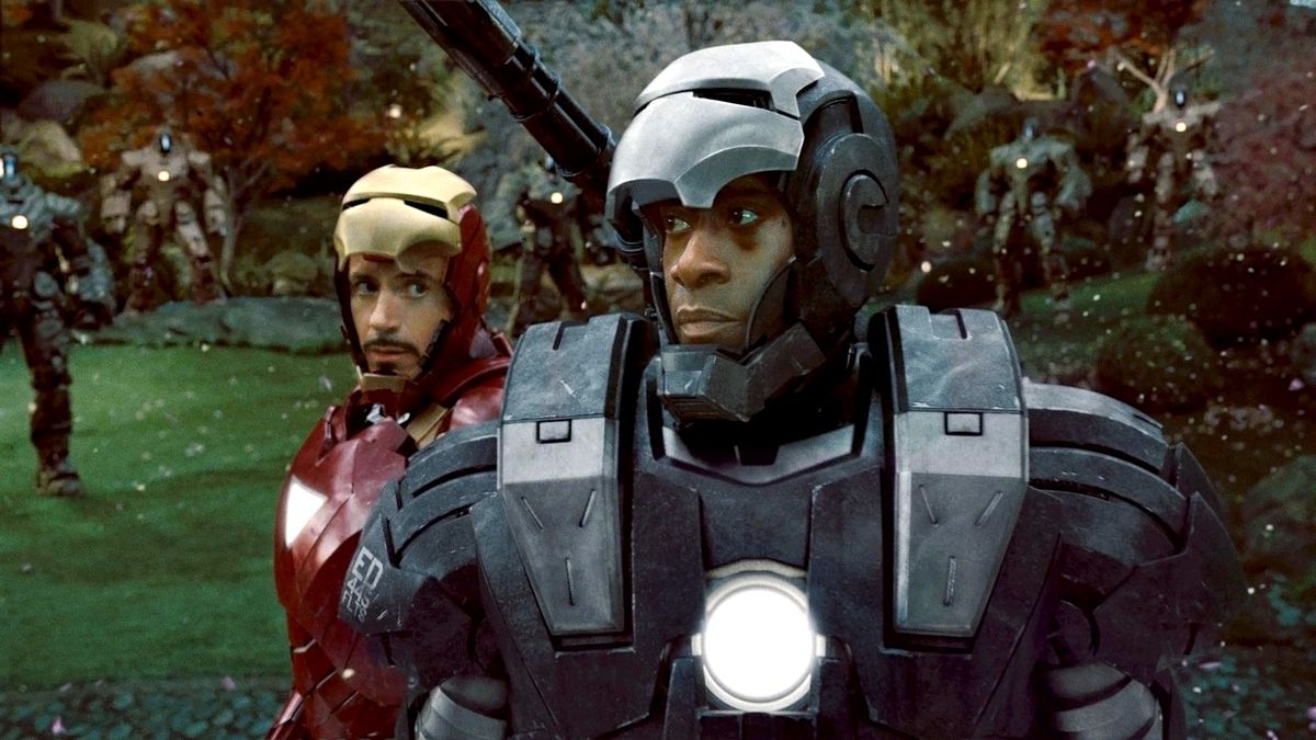 Don Cheadle’s Rhodey stands suited up as War Machine in front of a damaged Tony Stark in his Iron Man armor in Iron Man 2