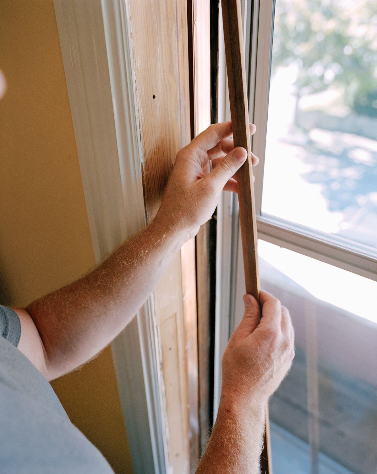Person pulling window beading from double hung window to prepare from weatherstripping.