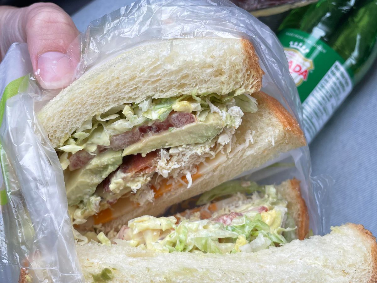 A sandwich filled with meat and vegetables, sliced in half to show its contents.