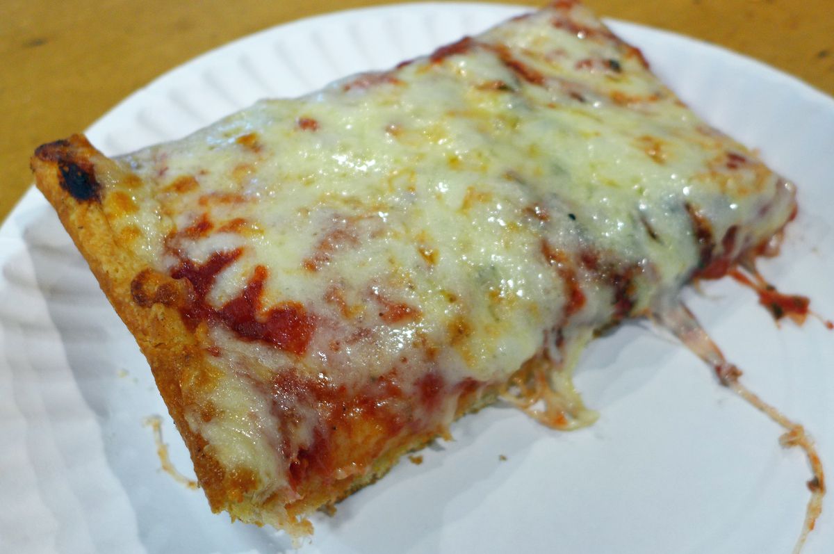 A thick rectangle of pizza slice with cheese cascading over the sides.