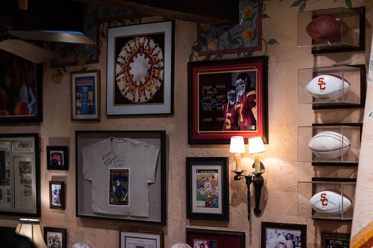 A wall with photos, tshirts, USC footballs, and historic figures at El Cholo in Los Angeles.
