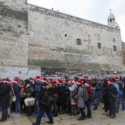 Christian pilgrims wearing red Santa hats wait in line to enter the Church of the Nativity, built atop the site where Christians believe Jesus Christ was born, on Christmas Eve, in the West Bank City of Bethlehem, Saturday, Dec. 24, 2016.