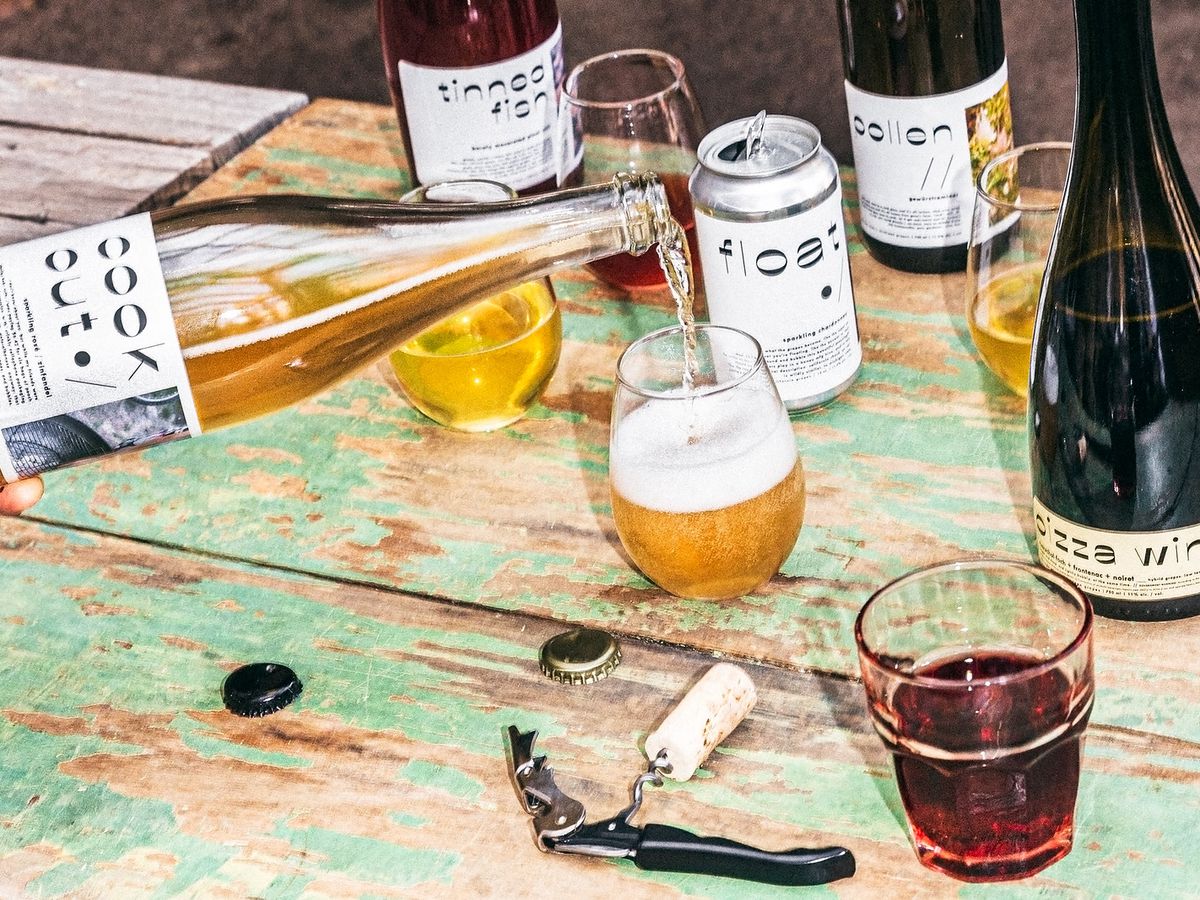 A bottle of wine poured into a glass on a picnic table.