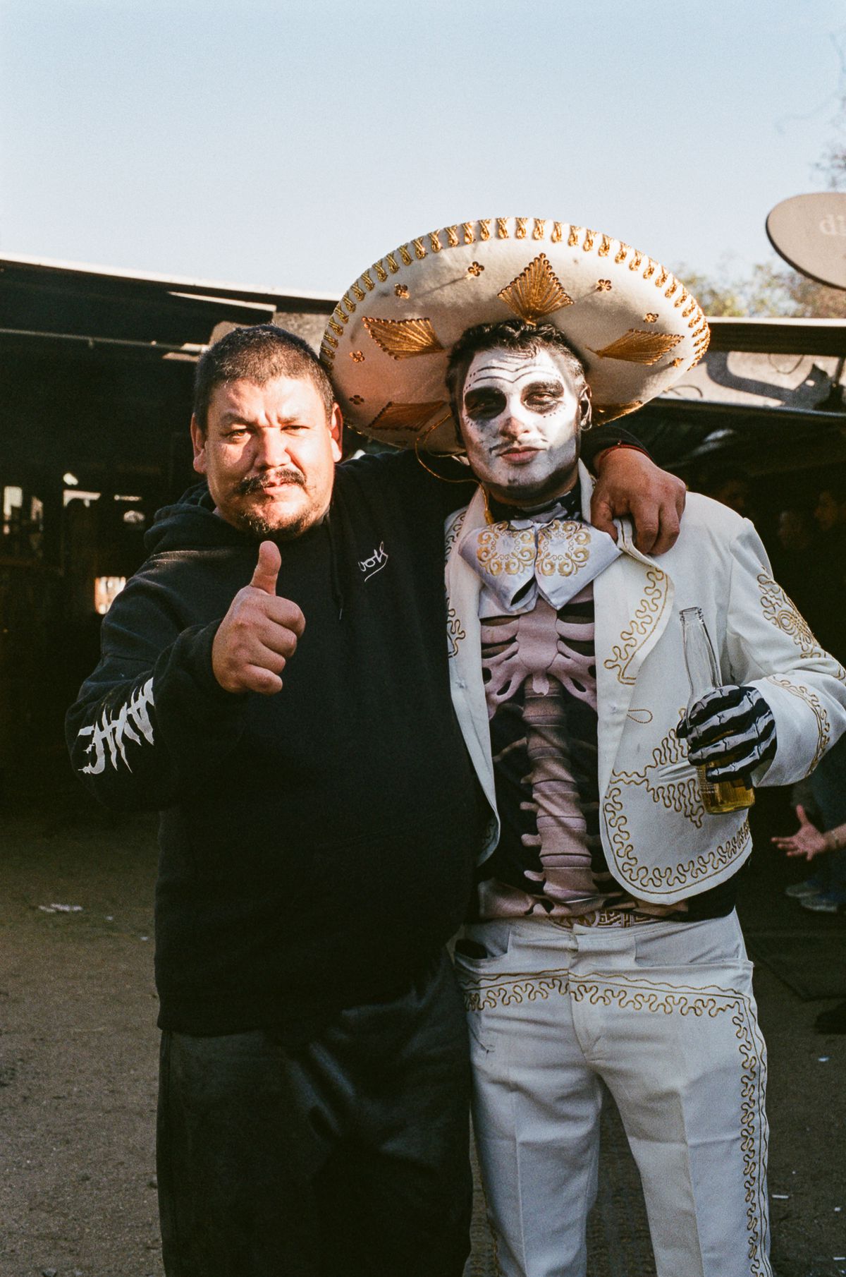 A costumed banda performer poses with a fan who’s holding his thumb up.