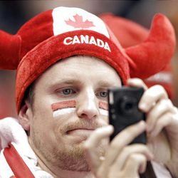A fan photographs a preliminary round men's ice hockey game between Canada and Norway at the 2010 Olympics in Vancouver.   