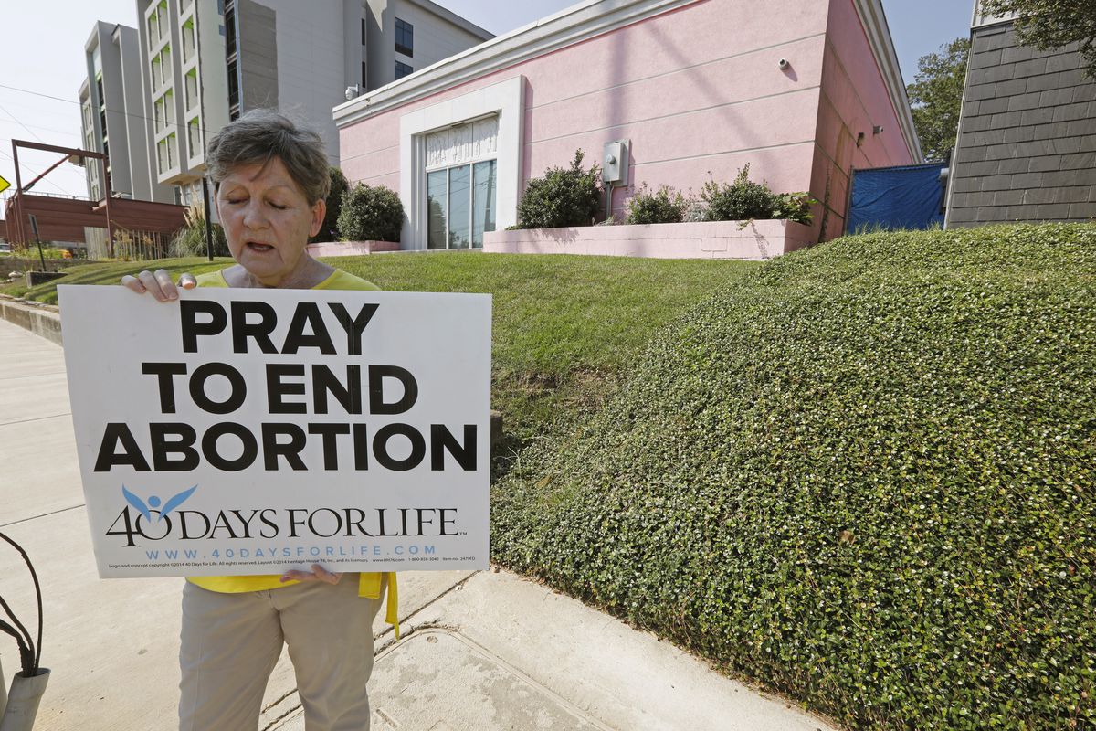 In this Oct. 2, 2019. file photo, an abortion opponent sings to herself outside the Jackson Womens Health Organization clinic in Jackson, Miss.