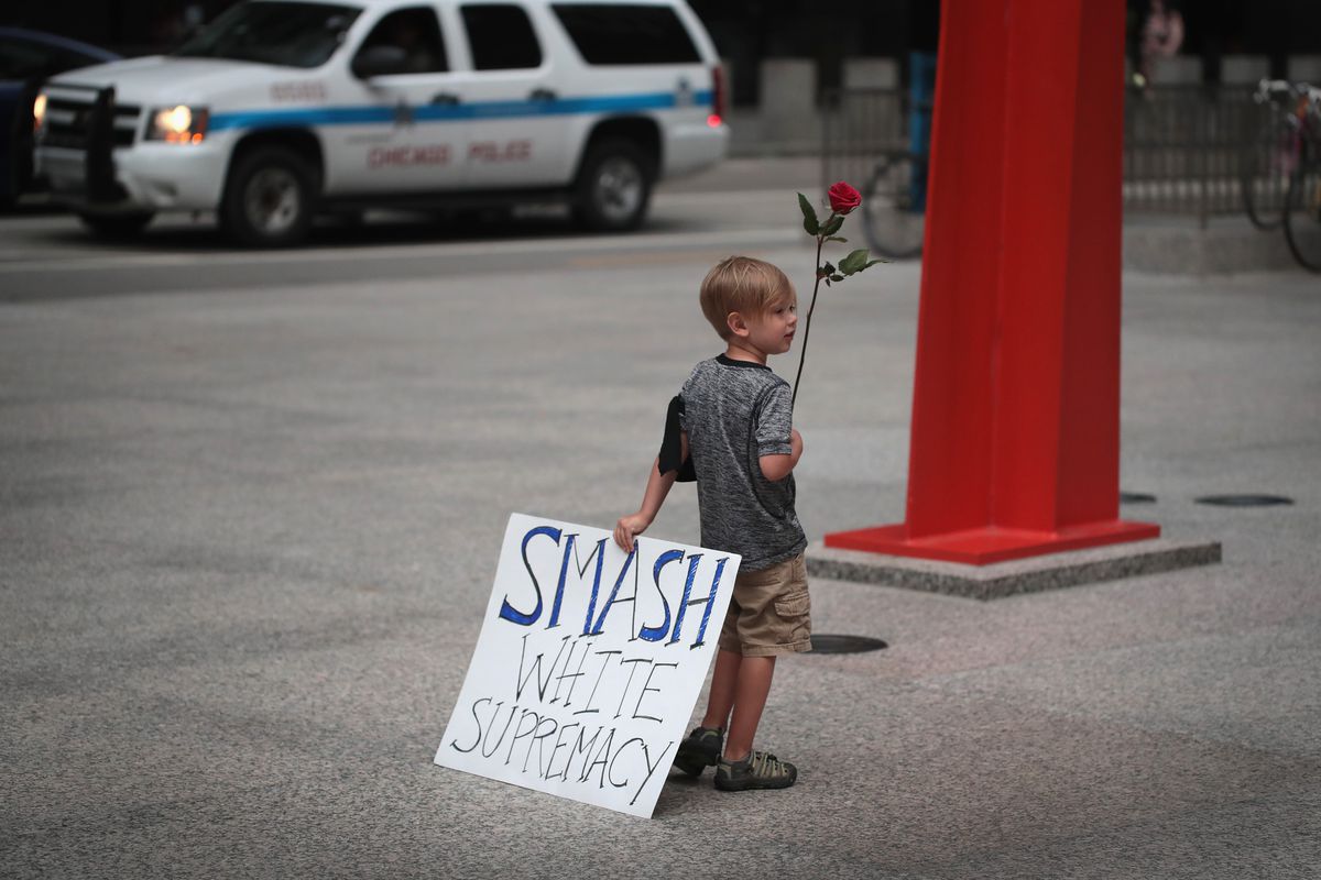 A young boy holds a sign that reads, “Smash white supremacy.”