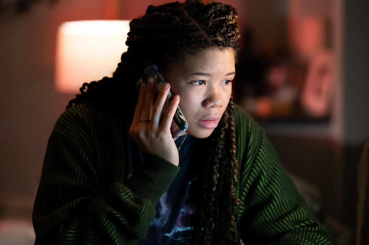 A young woman (Storm Reid) staring at a computer screen while holding a phone up to her ear in Missing.