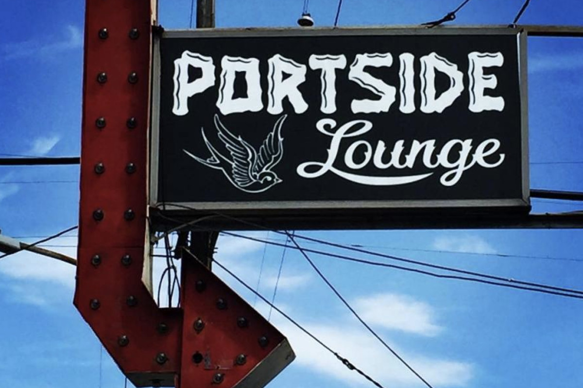 A large red arrow sign pointing to the right is attached to a black sign spelling out Portside Lounge.