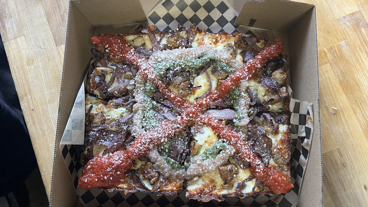 A Detroit-style pizza topped with several colorful sauces