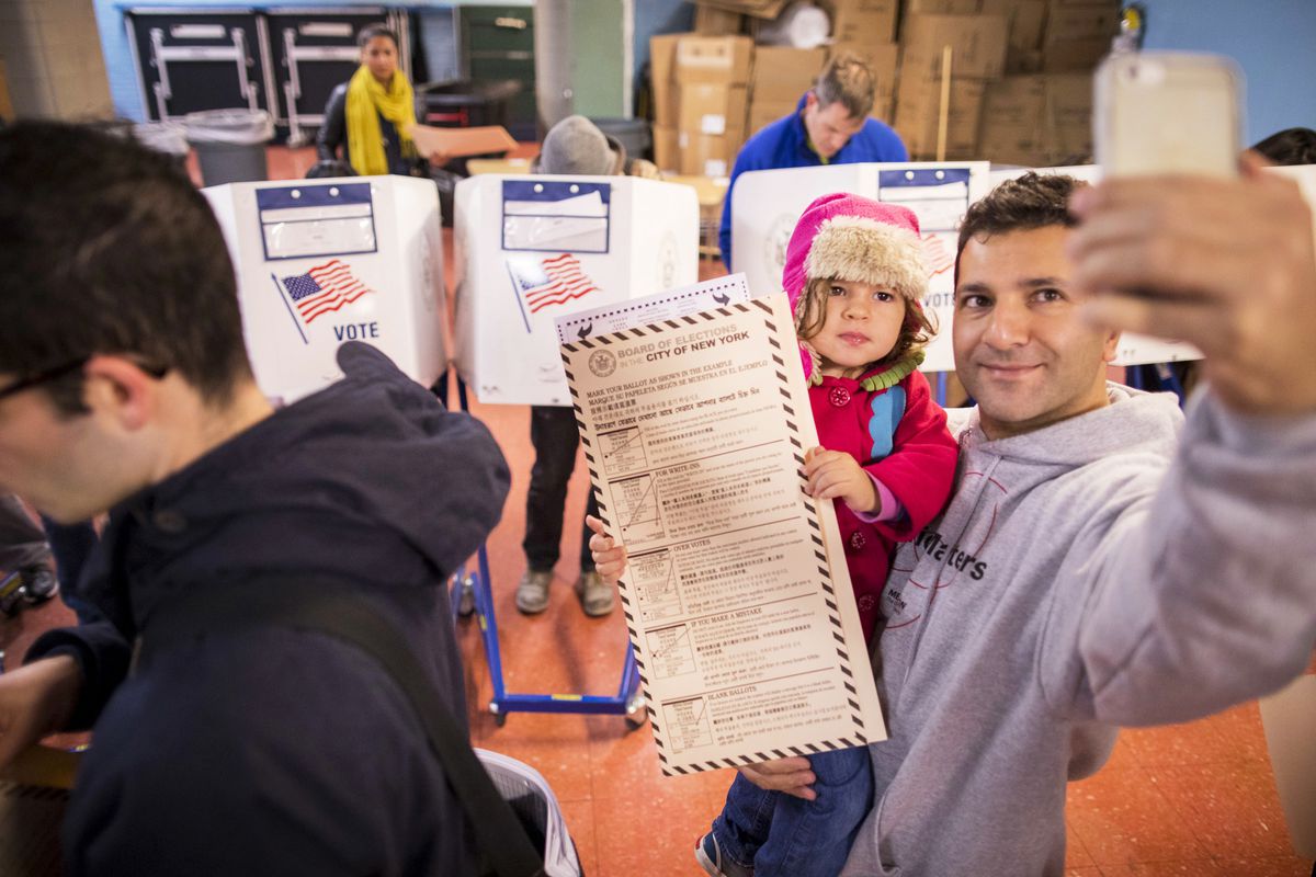 A man takes a selfie with his child as he waits to vote at a polling station in New York