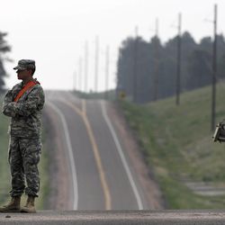 A soldier mans a roadblock to an evacuated area of forest, ranches and residences, in the Black Forest wildfire area, north of Colorado Springs, Colo., on Thursday, June 13, 2013.  The blaze in the Black Forest is now the most destructive in Colorado history, surpassing last year's Waldo Canyon fire, which burned 347 homes, killed two people and led to $353 million in insurance claims.(AP Photo/Brennan Linsley)