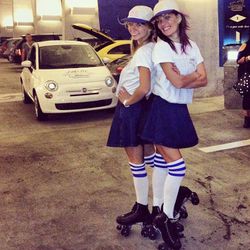 Two of the Colette Drive-Thru "carhops" (girls on Chrome Hearts-designed roller skates) with the pop-up's branded Fiat. 