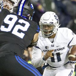 Utah State quarterback Damion Hobbs (11) runs with the ball toward Brigham Young defensive lineman Handsome Tanielu (92) during an NCAA college football game in Provo on Saturday, Nov. 26, 2016.