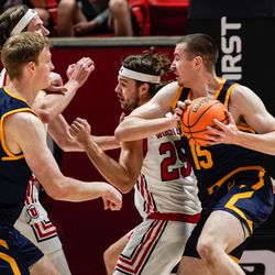 California forward Grant Anticevich, right, attempts to shoot past Utah defenders during an NCAA game at the Huntsman Center in Salt Lake City on Sunday, Dec. 5, 2021.